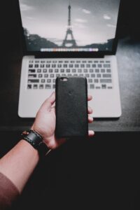 Person Holding Iphone Near Macbook Pro